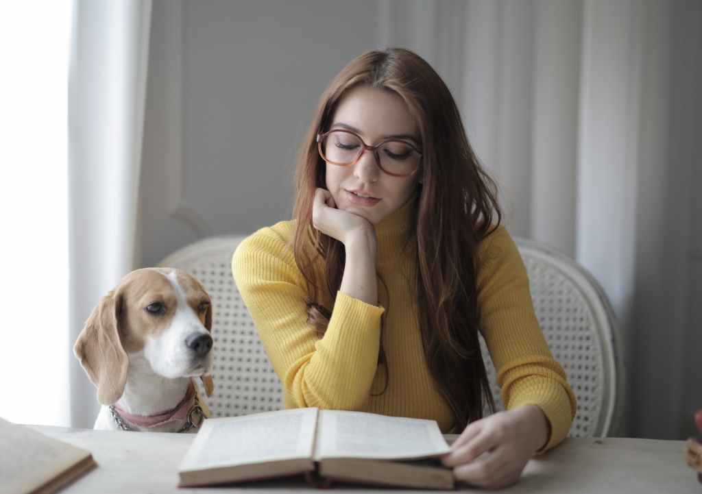 Una chica leyendo un libro en compañía de un perro